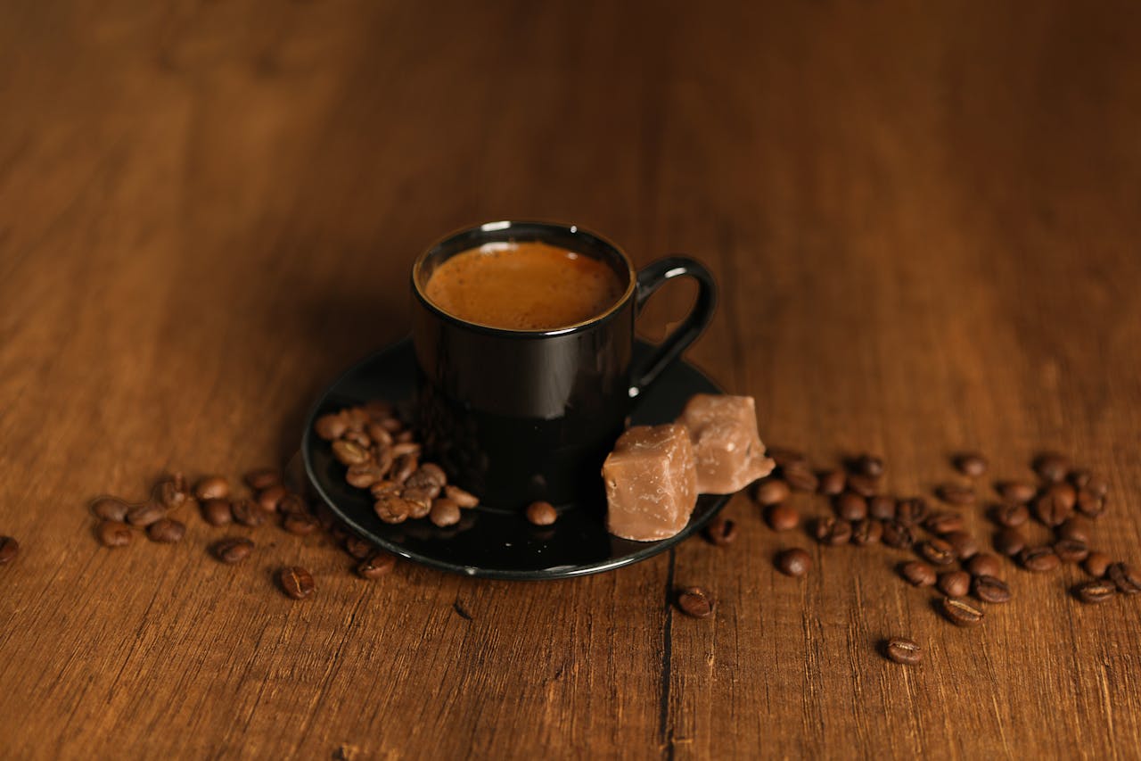 about-img-01 A black cup of espresso surrounded by coffee beans on a wooden table, adding warmth and richness.